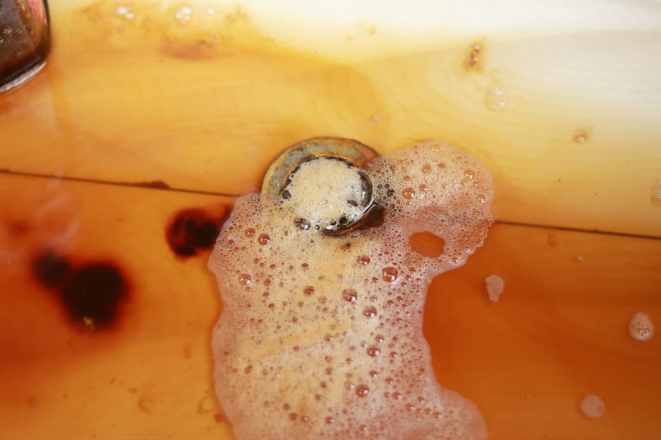 Brown, foamy water collecting around a drain