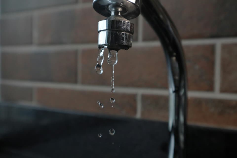 Water dripping from the tip of a kitchen faucet
