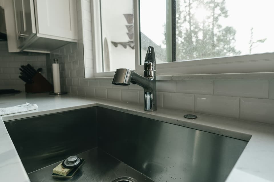 A stainless steel kitchen sink and faucet below a window